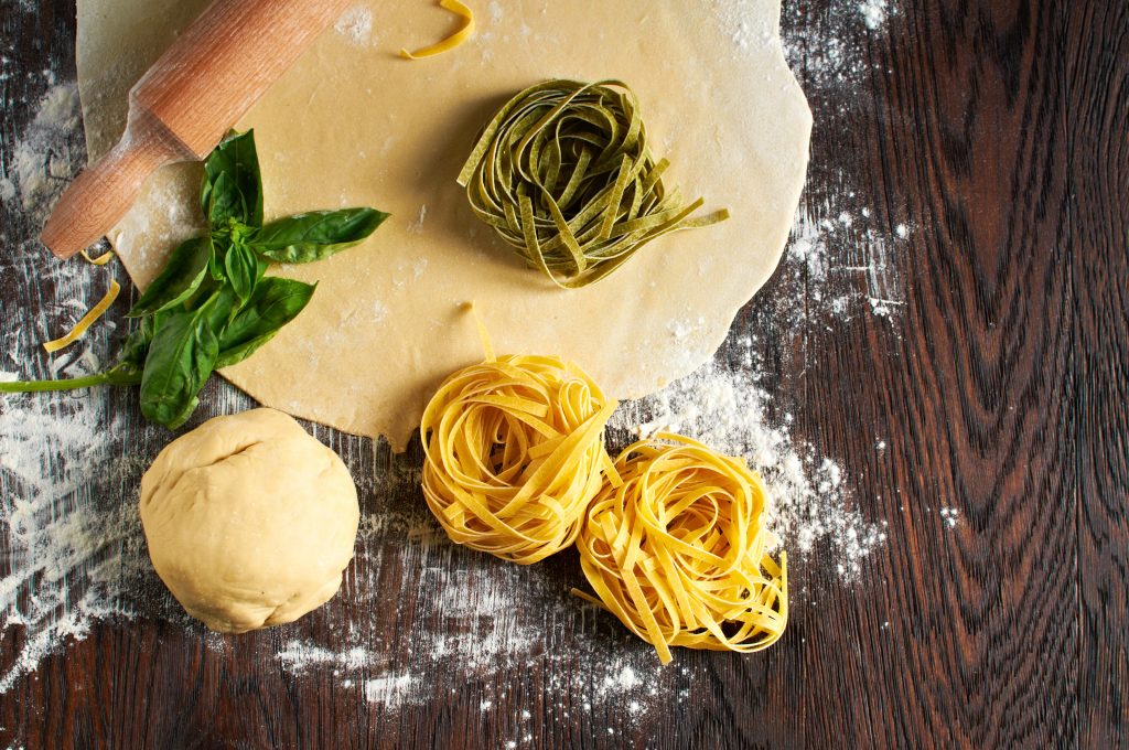 Italian pasta on wooden table with dough